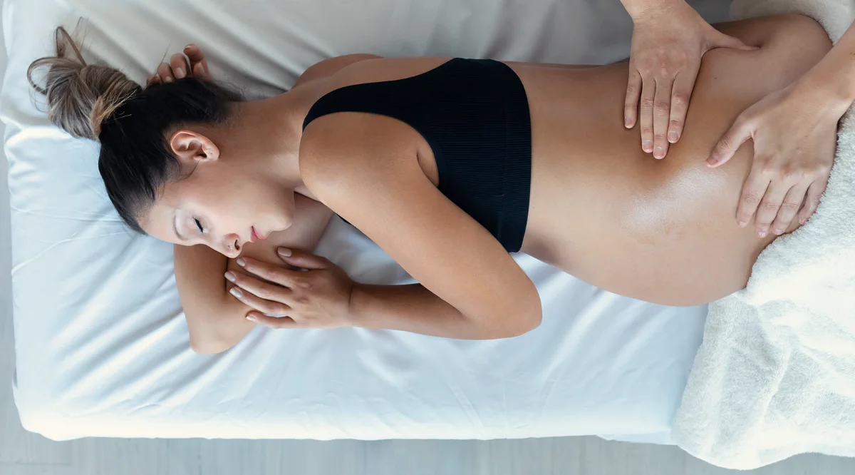 Pregnant woman relaxing in a side-lying position during prenatal massage at Soma in Milton
